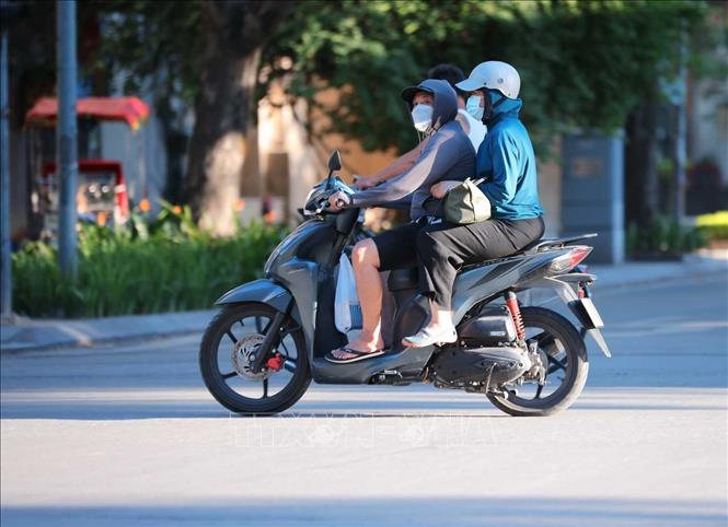 Người dân khi ra đường phải trang bị kín mít với áo chống nắng, khẩu trang, kính râm để hạn chế cái nóng oi bức. Ảnh: Hoàng Hiếu - TTXVN