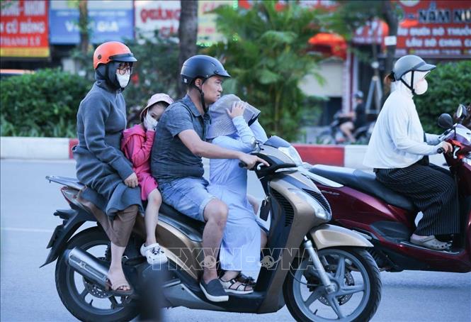 Người dân khi ra đường phải trang bị kín mít với áo chống nắng, khẩu trang, kính râm để hạn chế cái nóng oi bức. Ảnh: Hoàng Hiếu - TTXVN