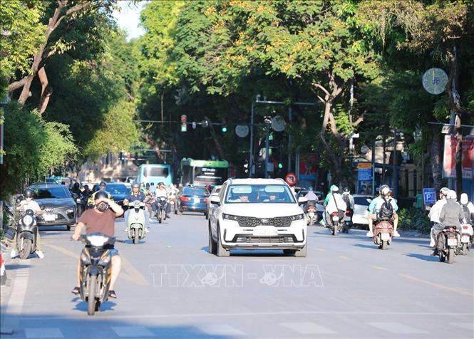 Ánh nắng chói chang lúc 17h33' khiến người đi trên đường gặp nhiều khó khăn khi tham gia giao thông. Ảnh: Hoàng Hiếu - TTXVN