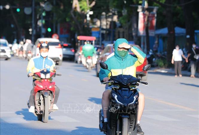 Ánh nắng chói chang lúc 17h33' khiến người đi trên đường gặp nhiều khó khăn khi tham gia giao thông. Ảnh: Hoàng Hiếu - TTXVN