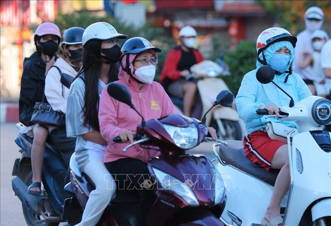Người dân khi ra đường phải trang bị kín mít với áo chống nắng, khẩu trang, kính râm để hạn chế cái nóng oi bức. Ảnh: Hoàng Hiếu - TTXVN
