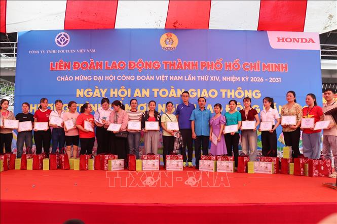 Phó Chủ tịch LĐLĐ TP. Hồ Chí Minh Lê Văn Hòa trao giấy chứng nhận làm việc tại Công ty trách nhiệm hữu hạn Pouyuen Việt Nam trên 15 năm và tặng 1 chỉ vàng cho người lao động tại Ngày hội “An toàn giao thông” và Chương trình “Cảm ơn người lao động”. Ảnh: Thanh Vũ - TTXVN