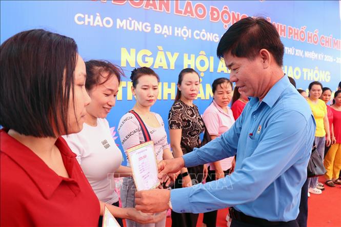 Phó Chủ tịch LĐLĐ TP. Hồ Chí Minh Phạm Chí Tâm trao giấy chứng nhận làm việc tại Công ty trách nhiệm hữu hạn Pouyuen Việt Nam trên 15 năm và tặng 1 chỉ vàng cho người lao động tại Ngày hội “An toàn giao thông” và Chương trình “Cảm ơn người lao động”. Ảnh: Thanh Vũ - TTXVN