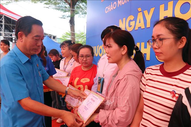 Phó Chủ tịch LĐLĐ TP. Hồ Chí Minh Lê Văn Hòa trao giấy chứng nhận làm việc tại Công ty trách nhiệm hữu hạn Pouyuen Việt Nam trên 15 năm và tặng 1 chỉ vàng cho người lao động tại Ngày hội “An toàn giao thông” và Chương trình “Cảm ơn người lao động”. Ảnh: Thanh Vũ - TTXVN