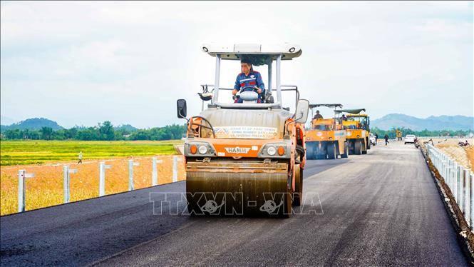 Thi công hạng mục thảm nhựa trên Quốc lộ 8C. Ảnh: Hữu Quyết – TTXVN