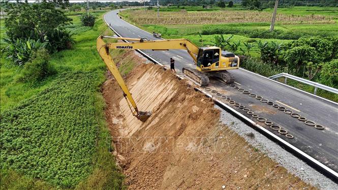 Máy móc thi công tại phần mái taluy trên tuyến Quốc lộ 8C. Ảnh: Hữu Quyết – TTXVN