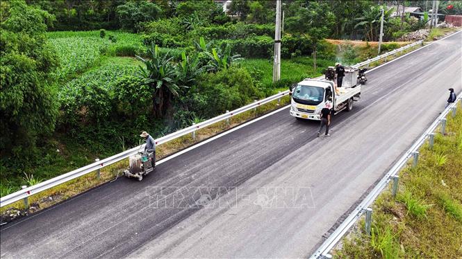 Đơn vị thi công triển khai hạng mục sơn vạch kẻ đường tại tuyến Quốc lộ 8C đoạn qua xã Hương Sơn. Ảnh: Hữu Quyết - TTXVN