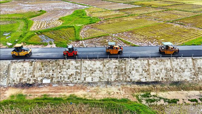 Công ty TNHH Như Nam huy động nhiều máy móc để tăng tốc thi công hạng mục thảm bêtông nhựa. Ảnh: Hữu Quyết – TTXVN