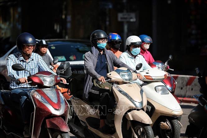 Người tham gia giao thông trên các tuyến phố trung tâm Hà Nội phải trang bị kín mít quần áo chống nắng, kính mát và khẩu trang để chống chọi với nền nhiệt tăng cao ngay từ sớm. Ảnh: Phạm Tuấn Anh - TTXVN