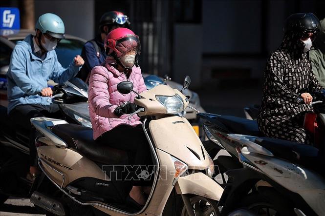 Người tham gia giao thông trên các tuyến phố trung tâm Hà Nội phải trang bị kín mít quần áo chống nắng, kính mát và khẩu trang để chống chọi với nền nhiệt tăng cao ngay từ sớm. Ảnh: Phạm Tuấn Anh - TTXVN