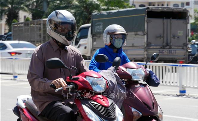 Người dân mặc các trang phục chống nắng khi ra đường. Ảnh: Văn Đức - TTXVN 
