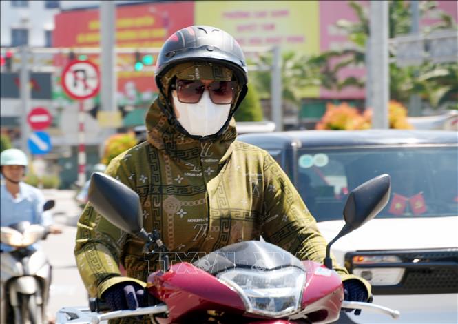 Người dân mặc các trang phục chống nắng khi ra đường. Ảnh: Văn Đức - TTXVN 