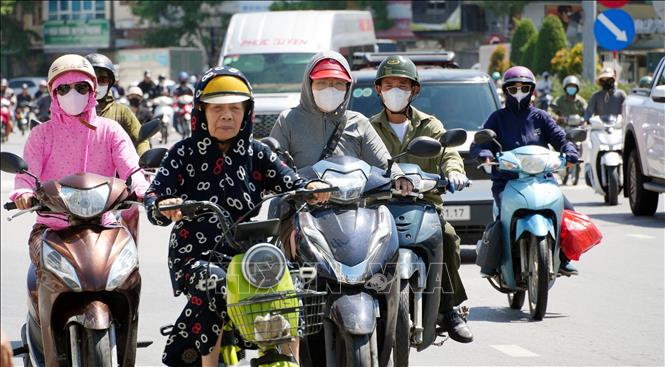 Người dân mặc các trang phục chống nắng khi ra đường. Ảnh: Văn Đức - TTXVN 