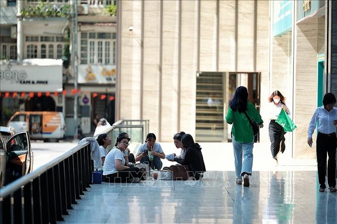 Nhiều bạn trẻ chọn ngồi tại khu vực có mái che, tránh nắng trong giờ nghỉ trưa. Ảnh: Phạm Tuấn Anh - TTXVN