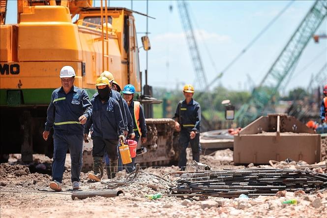 Nhóm công nhân tranh thủ di chuyển, nghỉ ngắn giữa ca làm việc ngoài trời tại công trường xây dựng. Ảnh: Phạm Tuấn Anh - TTXVN