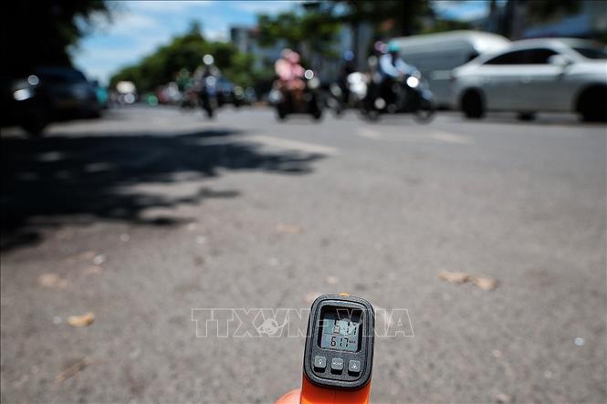 Thiết bị đo nhiệt cho thấy nhiệt độ bề mặt mặt đường ngoài trời lên tới hơn 61 độ C vào thời điểm giữa trưa ngày 25/5. Ảnh: Phạm Tuấn Anh - TTXVN