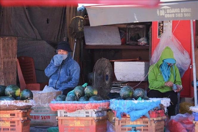 Thời tiết ngoài trời tăng cao khiến các tiểu thương chợ Long Biên vẫn phải mặc đồ chống nắng để tránh mất nhiệt cơ thể. Ảnh: Hoàng Hiếu - TTXVN