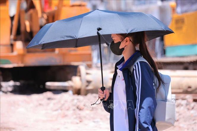 Người dân tìm mọi cách chống nắng khi phải di chuyển trên đường. Ảnh: Hoàng Hiếu - TTXVN