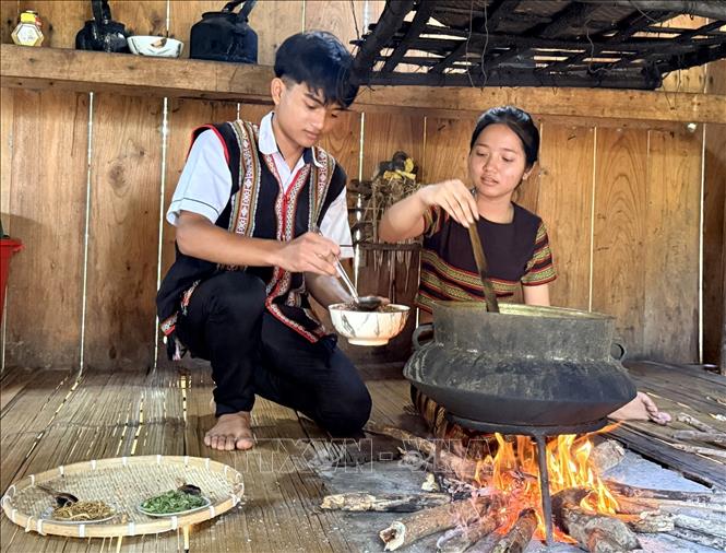 Em Đinh Thị Quỳnh Như (lớp 8) và Đinh Văn Chinh (lớp 9), học sinh Trường PTDTBT Tiểu học và THCS Sơn Tân (xã Sơn Tây) rang gạo lúa rẫy để làm trà. Ảnh: Đinh Hương - TTXVN