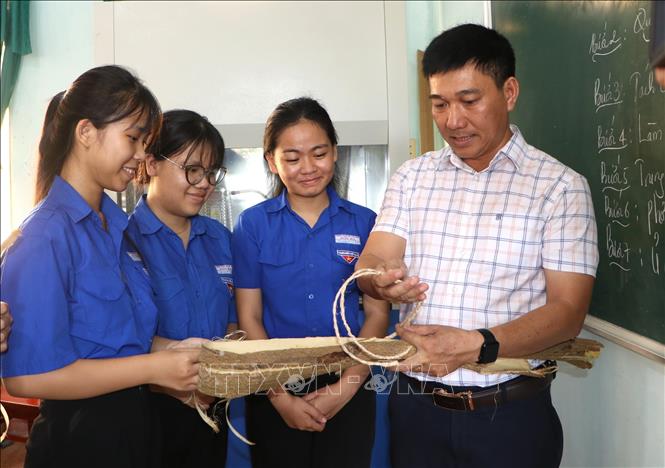 Thầy giáo Trường THPT Sơn Hà hướng dẫn quy trình xử lý vỏ keo để tạo ra sản phẩm sợi vỏ keo. Ảnh: Đinh Hương - TTXVN