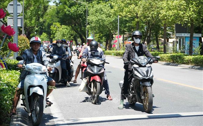 Người dân mặc đồ bảo hộ tránh nắng nóng gay gắt khi tham gia giao thông trên đường Lê Lợi, phường Thuận Hóa (Huế). Ảnh: Nguyên Lý-TTXVN