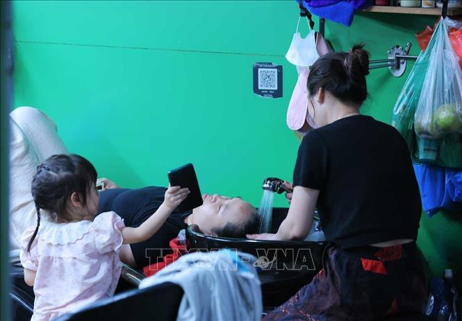  Người dân đến chợ Trương Định để gội đầu, làm mát cơ thể để chống chọi với thời tiết nắng nóng gay gắt tại Hà Nội. Ảnh: Hoàng Hiếu - TTXVN