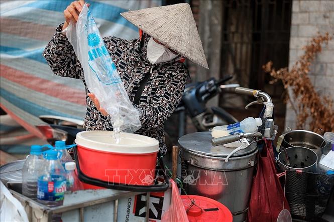 Một người bán hàng rong giữ đồ uống mát lạnh phục vụ khách giữa đợt nắng nóng đầu hè. Ảnh: Phạm Tuấn Anh - TTXVN