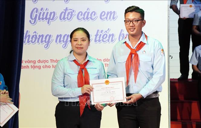 Chị Trịnh Thị Hiền Trân, Phó Bí thư Thành đoàn, Chủ tịch Hội đồng Đội, Chủ tịch Hội đồng Huấn luyện công tác Đội TP. Hồ Chí Minh trao giấy chứng nhận danh hiệu “Giáo viên làm Tổng phụ trách Đội giỏi” năm học 2025 - 2026 cho anh Trần Điền Khang, Trường THCS Bình Đông, phường Phú Định. Ảnh: Trung Tuyến - TTXVN
