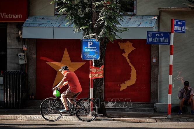 Người dân đạp xe trên phố khi không khí còn dịu mát của buổi sáng sớm. Ảnh: Phạm Tuấn Anh - TTXVn