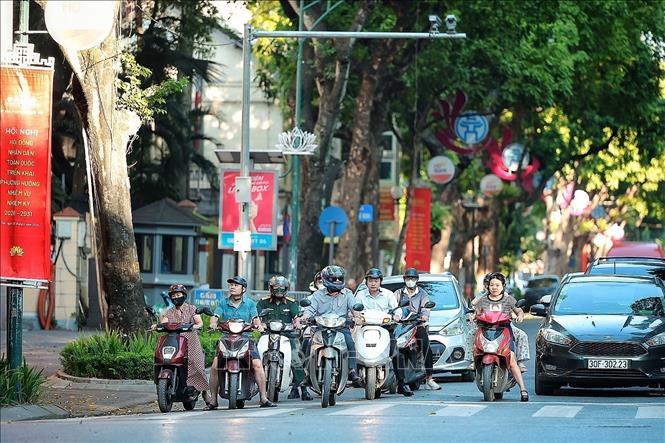 Nhiều người tranh thủ đi làm sớm hơn mọi ngày để tránh giờ cao điểm và nắng lên. Ảnh: Phạm Tuấn Anh - TTXVN