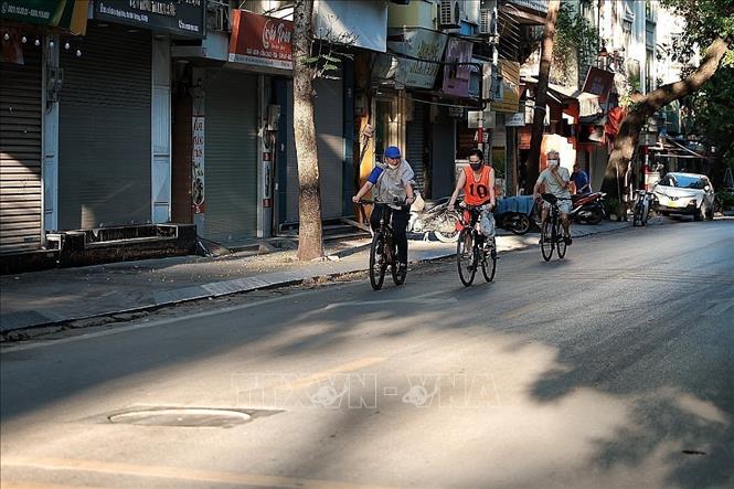 Người dân đạp xe tập thể dục trên phố từ rất sớm để kịp trở về nhà khi nhiệt độ chưa tăng cao. Ảnh: Phạm Tuấn Anh - TTXVN