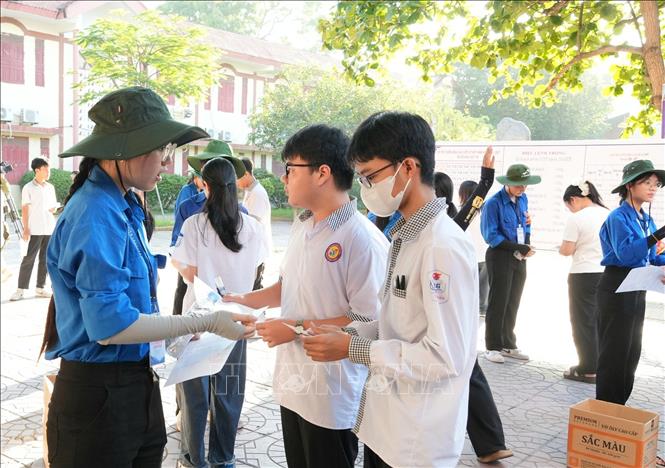 Đoàn viên, thanh niên tình nguyện hỗ trợ thí sinh kiểm tra các vật dụng trước khi vào phòng thi để tránh sai sót. Ảnh: Đồng Thúy - TTXVN