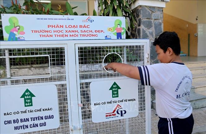 Học sinh trường Tiểu học Cần Thạnh 2, xã Cần Giờ (Thành phố Hồ Chí Minh) gom rác vào thùng phân loại rác. Ảnh: Hồng Đạt - TTXVN