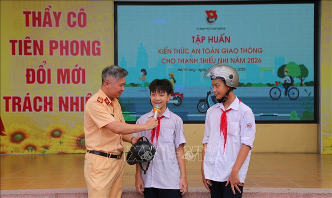 Đại diện Phòng Cảnh sát giao thông, Công an thành phố Hải Phòng hướng dẫn học sinh sử dụng mũ bảo hiểm an toàn. Ảnh: Minh Thu - TTXVN