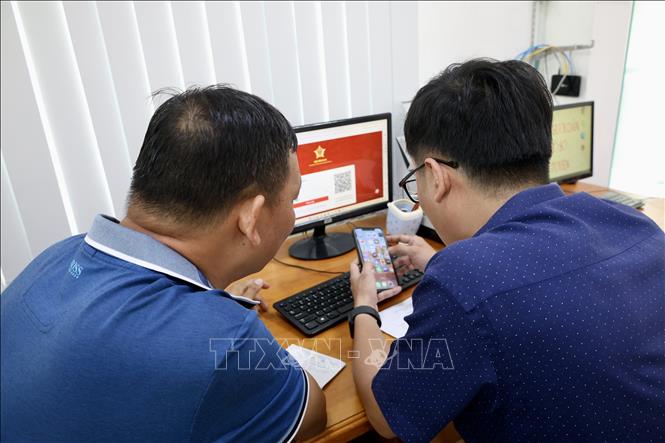 Cán bộ phường Long Xuyên (An Giang) hỗ trợ người dân đăng nhập ứng dụng VNeID để thực hiện thủ tục hành chính trực tuyến. Ảnh: Thanh Sang - TTXVN
