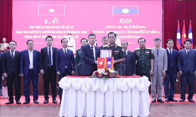 Thiếu tướng Tui Phommixay (phải), Chính ủy Bộ Chỉ huy quân sự tỉnh Oudomxay và Đại tá Dư Công Thịnh, Đội trưởng Đội Quy tập mộ liệt sỹ Quân khu 2 trao Biên bản bàn giao 9 hài cốt liệt sĩ. Ảnh: Xuân Tú - PV TTXVN tại Lào