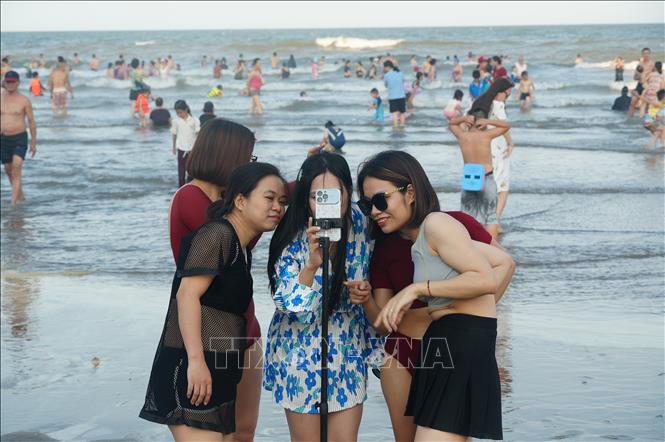 Các bạn trẻ thich thú quay video ghi lại những khoảnh khắc đẹp tại biển Sầm Sơn. Ảnh: Hoa Mai - TTXVN