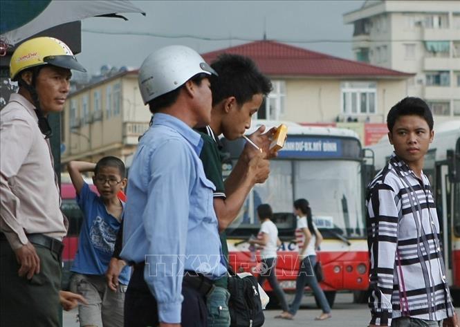 Một thanh niên thản nhiên hút thuốc lá tại nơi đông người ở Bến xe khách Mỹ Đình (Hà Nội). Ảnh: Phạm Kiên - TTXVN