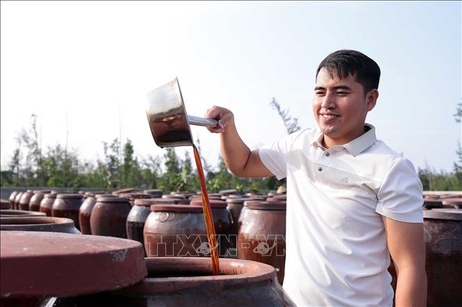 Anh Đặng Đình Minh, Giám đốc Hợp tác xã Thu mua và Chế biến thủy hải sản Chiến Thắng kiểm tra chất lượng sản phẩm nước mắm Luận Nghiệp. Ảnh: Hữu Quyết – TTXVN