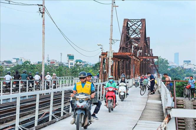 Xe máy, xe thô sơ và người đi bộ lưu thông trên mặt cầu được thảm mới. Ảnh: Hoàng Hiếu - TTXVN