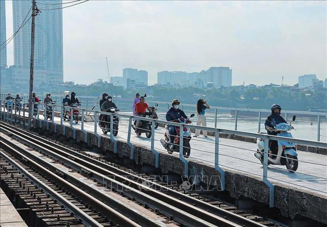 Xe máy, xe thô sơ và người đi bộ lưu thông trên mặt cầu được thảm mới. Ảnh: Hoàng Hiếu - TTXVN