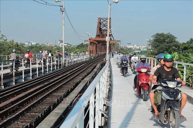 Xe máy, xe thô sơ và người đi bộ lưu thông trên mặt cầu được thảm mới. Ảnh: Hoàng Hiếu - TTXVN