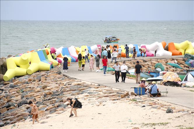 Rất đông du khách đến chụp ảnh, check in khi kè chắn sóng bãi biển đá Ông Địa được sơn nhiều màu sắc. Ảnh: Nguyễn Thanh - TTXVN