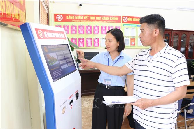 Công chức Trung tâm Phục vụ hành chính công xã Kim Thành hướng dẫn người dân làm thủ tục hành chính. Ảnh: Mạnh Tú - TTXVN