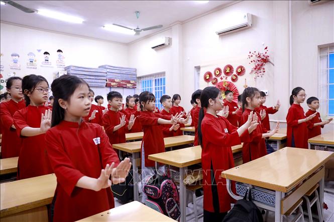 Trong tà áo dài đỏ rực rỡ, các học sinh say sưa thực hiện những động tác múa hát Xoan nhịp nhàng, góp phần tái hiện không gian văn hóa truyền thống ngay giữa lớp học. Ảnh: Hoàng Hùng – TTXVN