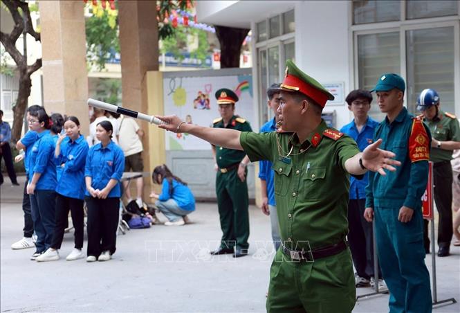 Lực lượng Công an phường Khương Đình làm nhiệm vụ đảm bảo an ninh trật tự, an toàn giao thông tại điểm thi Trường THCS Nguyễn Trãi. Ảnh: Phạm Kiên - TTXVN