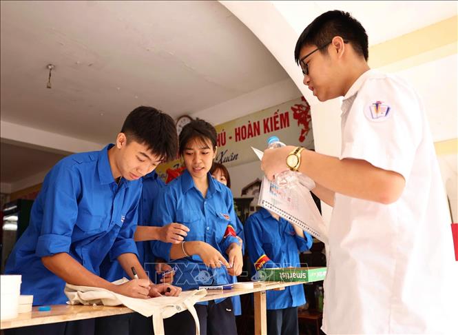 Thanh niên tình nguyện hướng dẫn thí sinh để vật dụng các nhân bên ngoài phòng thi theo quy định. Ảnh: Thanh Tùng - TTXVN