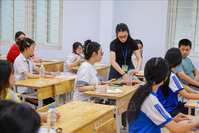 Giám thị kiểm tra đồ dùng mang theo của thí sinh phòng thi tại Điểm thi trường THPT Đoàn Kết - Hai Bà Trưng (phường Bạch Mai). Ảnh: Khánh Hoà - TTXVN