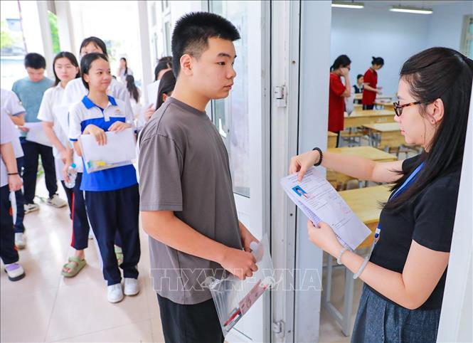 Giám thị kiểm tra thông tin thí sinh trước khi vào phòng thi tại Điểm thi trường THPT Đoàn Kết - Hai Bà Trưng (phường Bạch Mai). Ảnh: Khánh Hoà - TTXVN