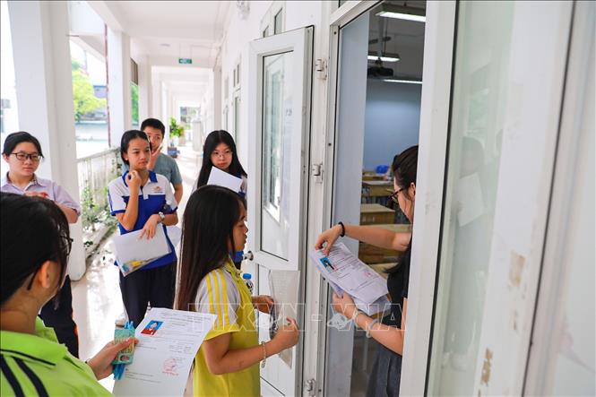 Giám thị kiểm tra thông tin thí sinh trước khi vào phòng thi tại Điểm thi trường THPT Đoàn Kết - Hai Bà Trưng (phường Bạch Mai). Ảnh: Khánh Hoà - TTXVN